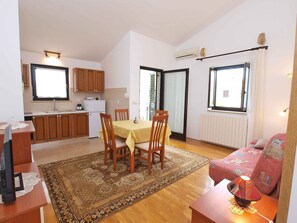 Cozy living space with a kitchen and dining area, featuring an oven, table with four chairs, and large windows.