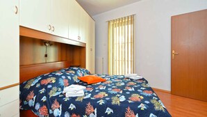 A bedroom with a bed, a window with blinds, a wardrobe, and a door. - Holiday apartment with air conditioning (Pula)