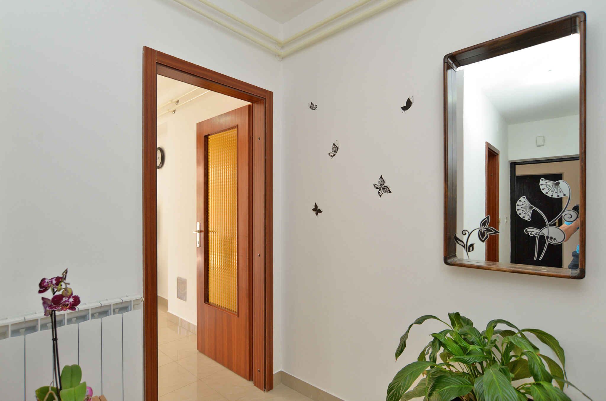 A hallway with a wooden door, a mirror, and decorative wall stickers.