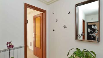 A hallway with a wooden door, a mirror, and decorative wall stickers.