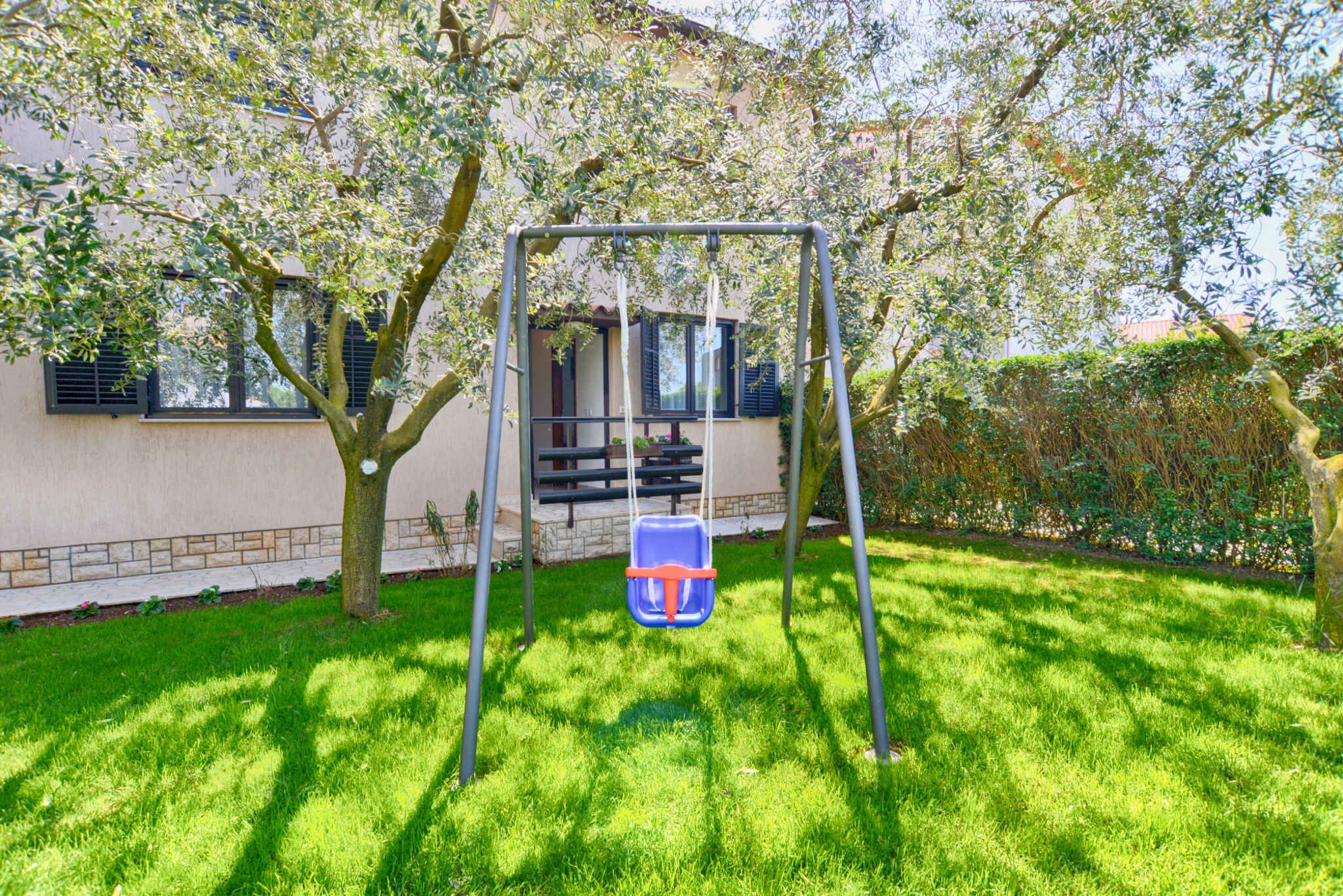 A swing set in a backyard with a house in the background.