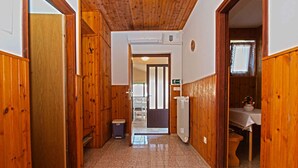A hallway with wooden walls and a tiled floor, leading to a room with a toilet and sink. - Holiday apartment with air conditioning and a view of the sea (Štinjan)
