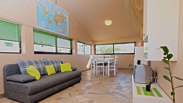 A cozy living area with a grey sofa, a small table, and a TV. - Holiday apartment with air conditioning and a view of the sea (Štinjan)
