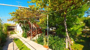 A narrow pathway flanked by greenery and a building with a red staircase. - Holiday apartment with air conditioning and a view of the sea (Štinjan)