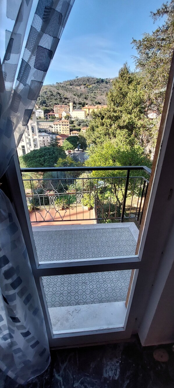 Un balcon doté d’un sol à motifs, d’une rambarde en métal et offrant une vue sur une ville avec ses bâtiments et ses arbres.