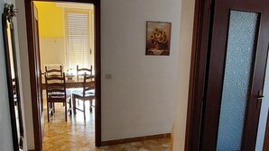 A hallway with a patterned floor leading to a dining area with chairs and a table.
