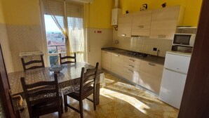 A kitchen with a dining table, chairs, a gas stove, cabinets, and a microwave.