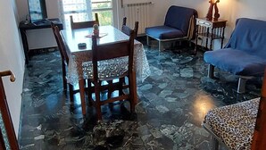 A room with a dining table, chairs, a sofa, and a lamp.