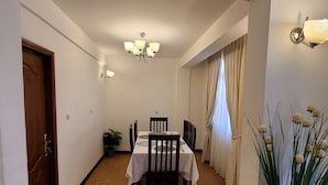 A dining area with a table set for four, a chandelier, and a potted plant. - Highly rated, clean, and spacious guest house in the Bethel area! Great discount (Kolfe Keranio)