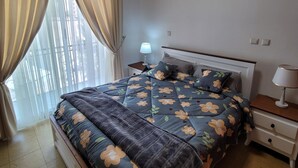 A bedroom with a bed, nightstands, a lamp, and a view through a window with curtains. - Highly rated, clean, and spacious guest house in the Bethel area! Great discount (Kolfe Keranio)