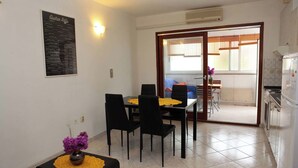 A dining area with a table and chairs, a vase with purple flowers, and a poster on the wall. - Holiday apartment with air conditioning (Pula)