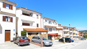 A row of white buildings with red-tiled roofs, parked cars, and a clear blue sky. - Holiday apartment with air conditioning (Pula)