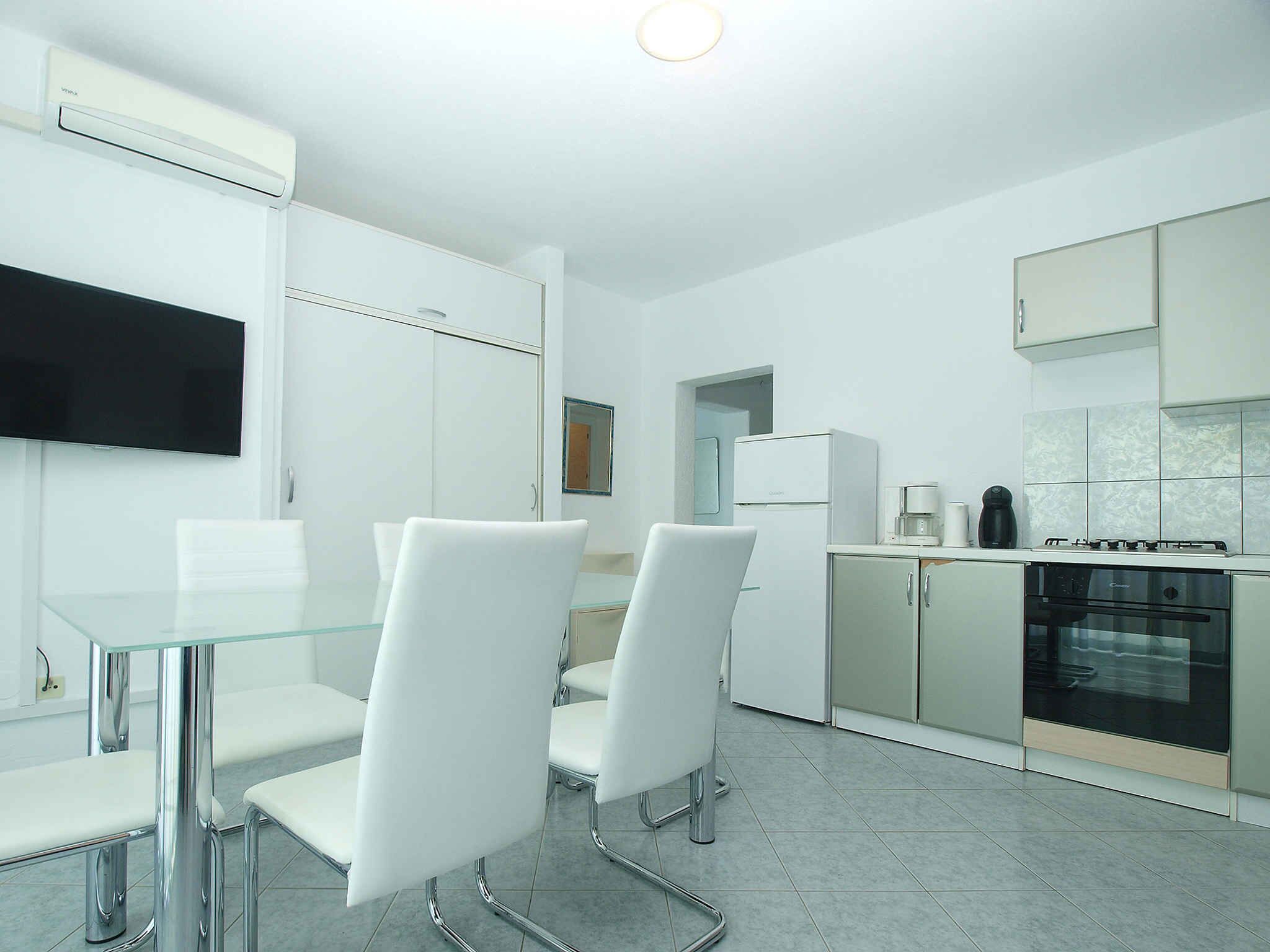 A modern kitchen with white cabinets, a built-in oven, and a coffee maker.