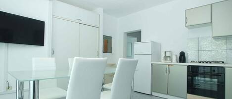 A modern kitchen with white cabinets, a built-in oven, and a coffee maker.