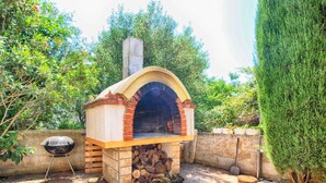 Un horno de ladrillo al aire libre con chimenea, una parrilla y un patio de piedra.