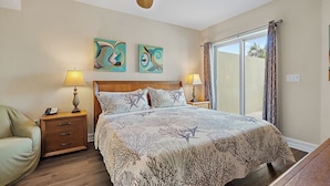 A bedroom with a bed, two nightstands, a ceiling fan, and artwork on the wall.