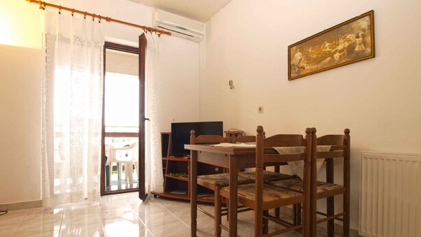 A dining area with a wooden table and chairs, a television, and a radiator. - Holiday apartment with air conditioning (Pula)