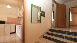 A kitchen with white cabinets, a microwave, and a stove. There is a staircase with black steps leading to another room. - Holiday apartment with air conditioning (Pula)