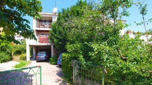 A residential building with a garage, a paved driveway, and a metal gate. - Holiday apartment with air conditioning (Pula)