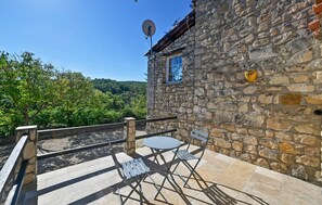 Ein Steinhaus mit Balkon, Satellitenschüssel und kleinem Fenster.