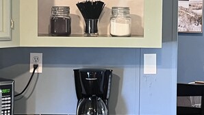 Et køkken med kaffestation, inklusive kaffemaskine, krukker og dekorative elementer.