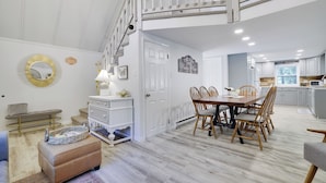 A spacious dining area with a high ceiling and a loft bedroom above. - Walk to Lake & Pool! Hot Tub, Air Hockey, Pool Table, Boat Rental, BBQ, Fire Pit (Pocono Lake)