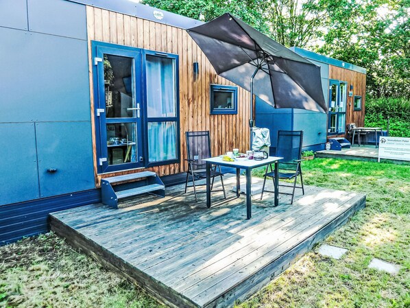 A modern building with a deck, a table with chairs, and a sign.