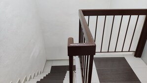 A staircase with alternating white and dark grey steps, a wooden handrail, and a white wall. - CLP Home near Sri Muniswarar Temple 2 (Perai)