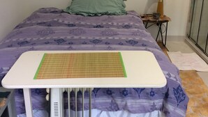 A bed with a purple floral bedspread, a green pillow, and a white bedside table with a lamp. - Toorak pristine central area pool, minutes to transport, shops, services. (Melbourne)