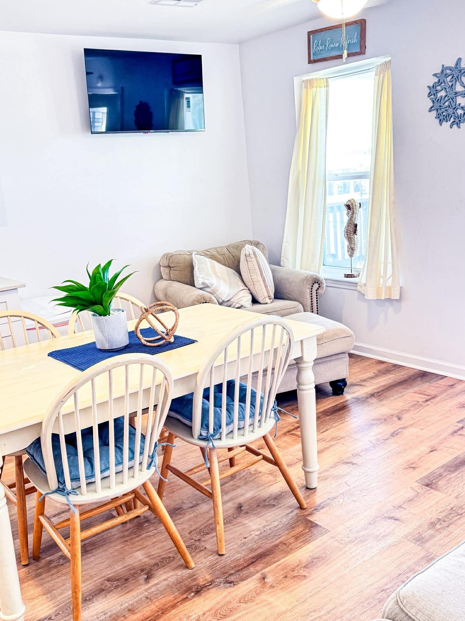 A dining area with a wooden table, white chairs, and a sofa.