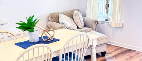 A dining area with a wooden table, white chairs, and a sofa.
