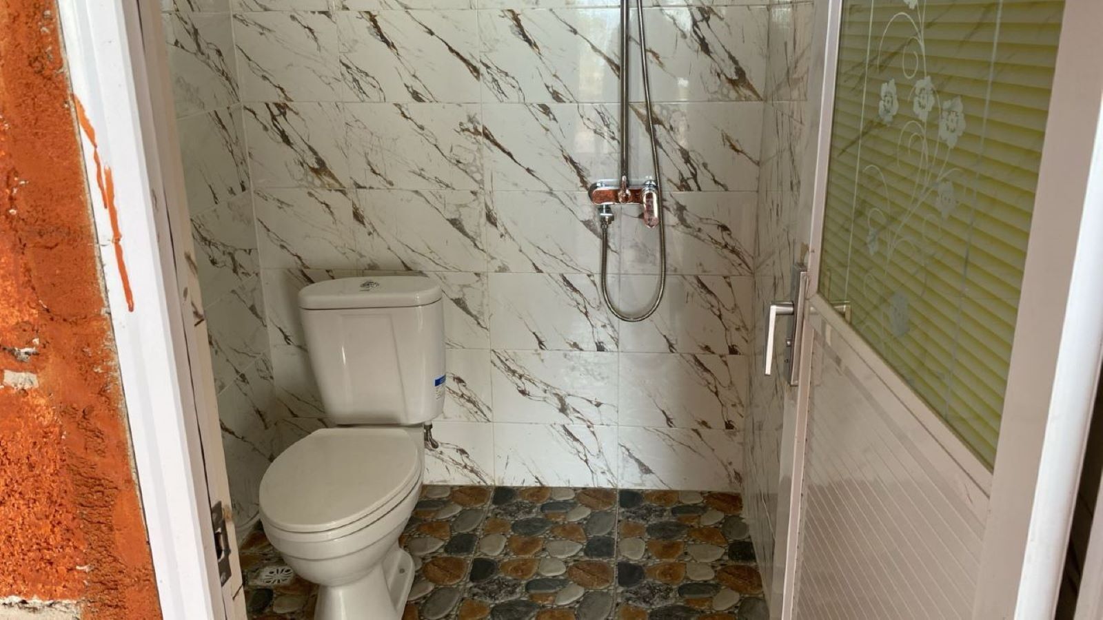 A bathroom with a toilet, shower, and tiled walls.