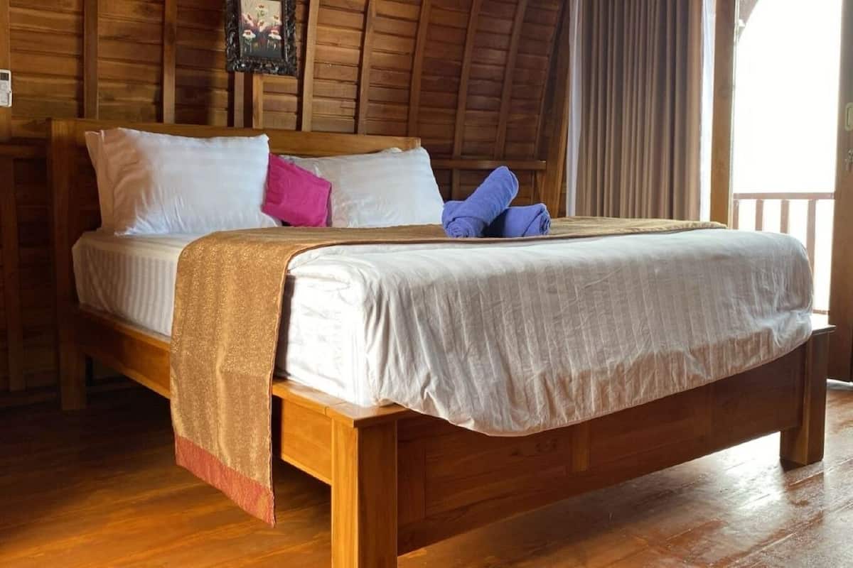 A wooden bed in a room with wooden walls and a wooden floor.
