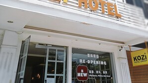 Exterior do Hotel Kozi com placa indicando a reabertura.