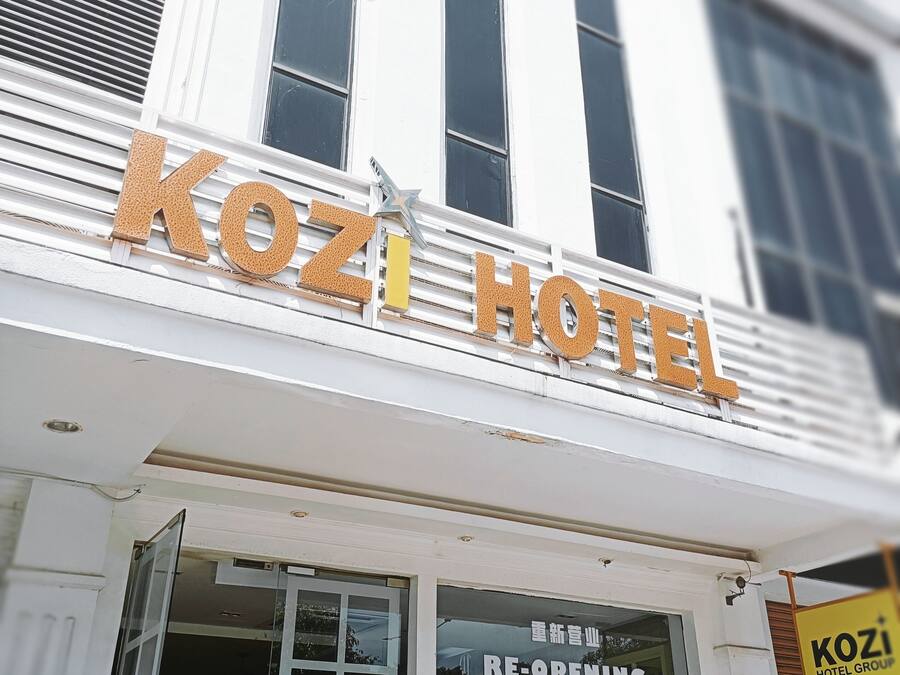 The exterior of Kozi Hotel with a sign indicating it is re-opening.