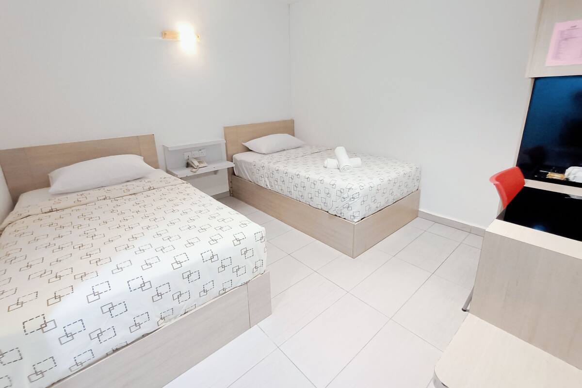 Habitación de hotel con dos camas, un escritorio y una silla.