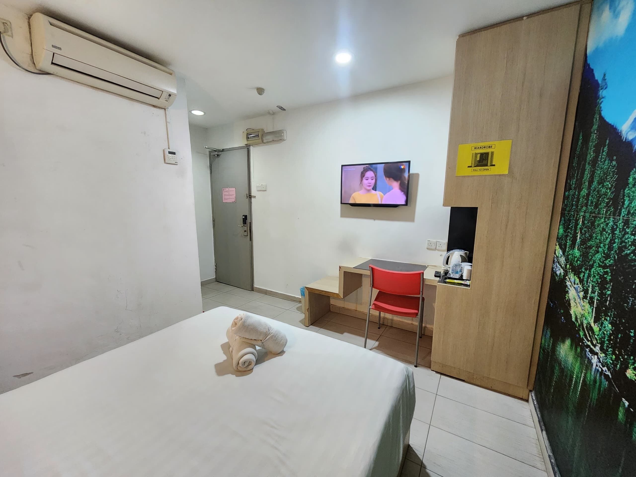 Una habitación de hotel con cama, televisión, escritorio y armario.