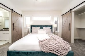 A bedroom with a bed, a large window, and a closet with sliding doors.