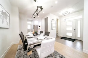 A modern dining area with a marble table, white chairs, and a black and white patterned rug.