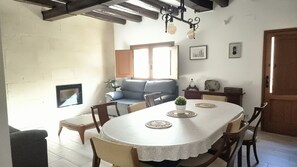 Enjoy meals in this inviting dining area with a round table for four, adjacent to a cozy living space.