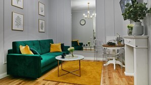 A modern living room with a green sofa, a coffee table, and framed artwork on the wall.