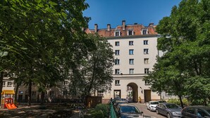 A park with playground equipment, a paved path, and a building with an archway entrance. - At the Fountain Apartment (Warszawa)