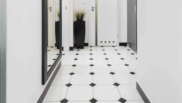 A hallway with a tiled floor, a potted plant, and a door with a vertical light strip. - At the Fountain Apartment (Warszawa)