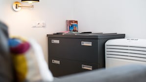 A modern room with a desk, a lamp, a heater, and a poster on the wall. - At the Fountain Apartment (Warszawa)