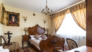 A traditional bedroom with a large bed, a chandelier, a painting, and a view of the outdoors. - At the Fountain Apartment (Warszawa)