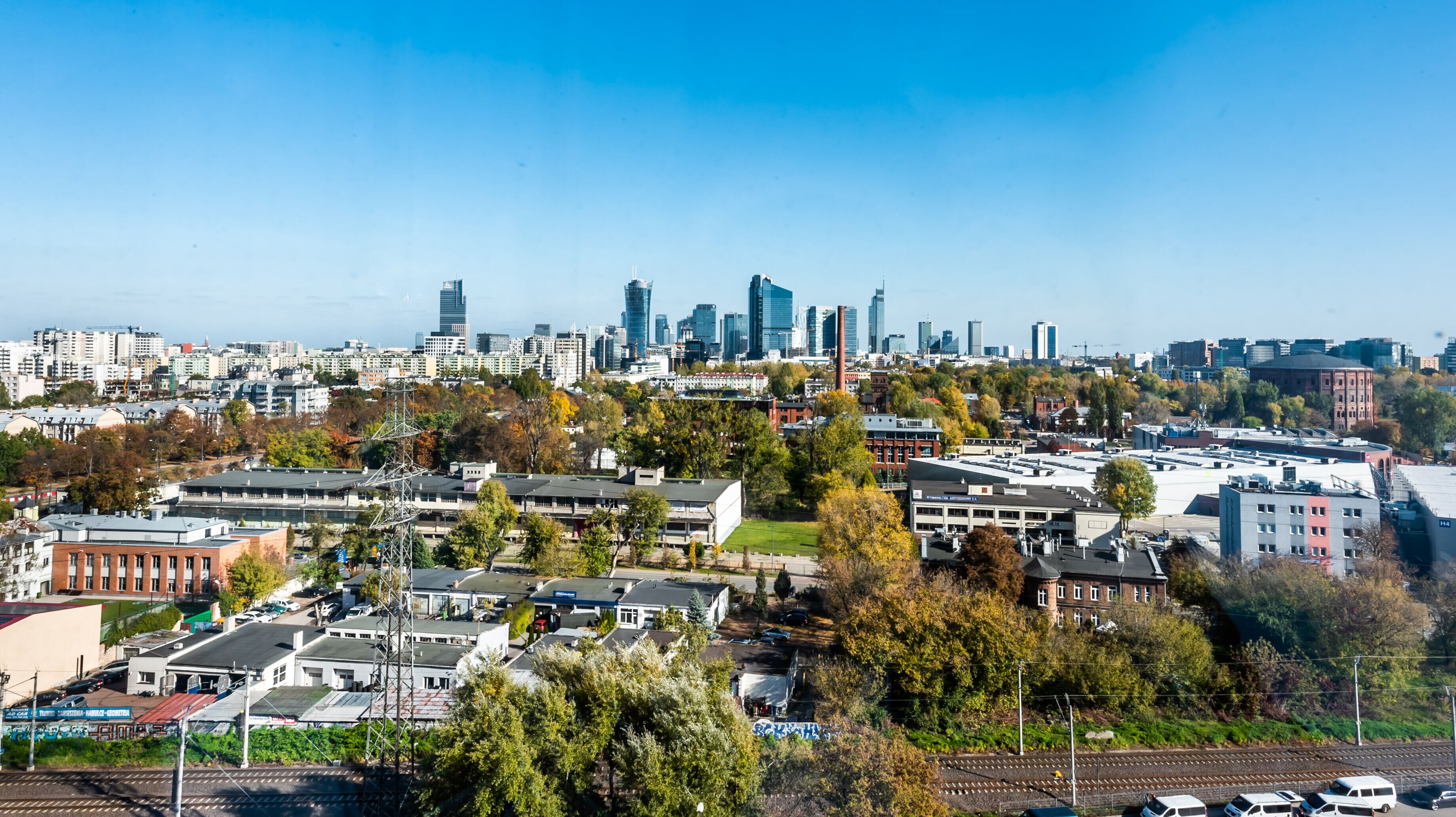 Eine Stadtansicht mit modernen Hochhäusern, einer Mischung aus Wohn- und Geschäftsgebäuden sowie einem Gleis.