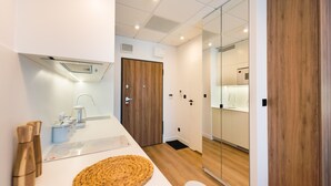 A modern bathroom with a white sink, wooden door, and a glass shower enclosure.