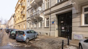 A row of parked cars along a cobblestone street adjacent to a building with a black door and a sign indicating a 4K service.