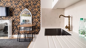 A modern kitchen with a black sink, white countertop, and a decorative window. - City Centre All In One Apartment (Warszawa)