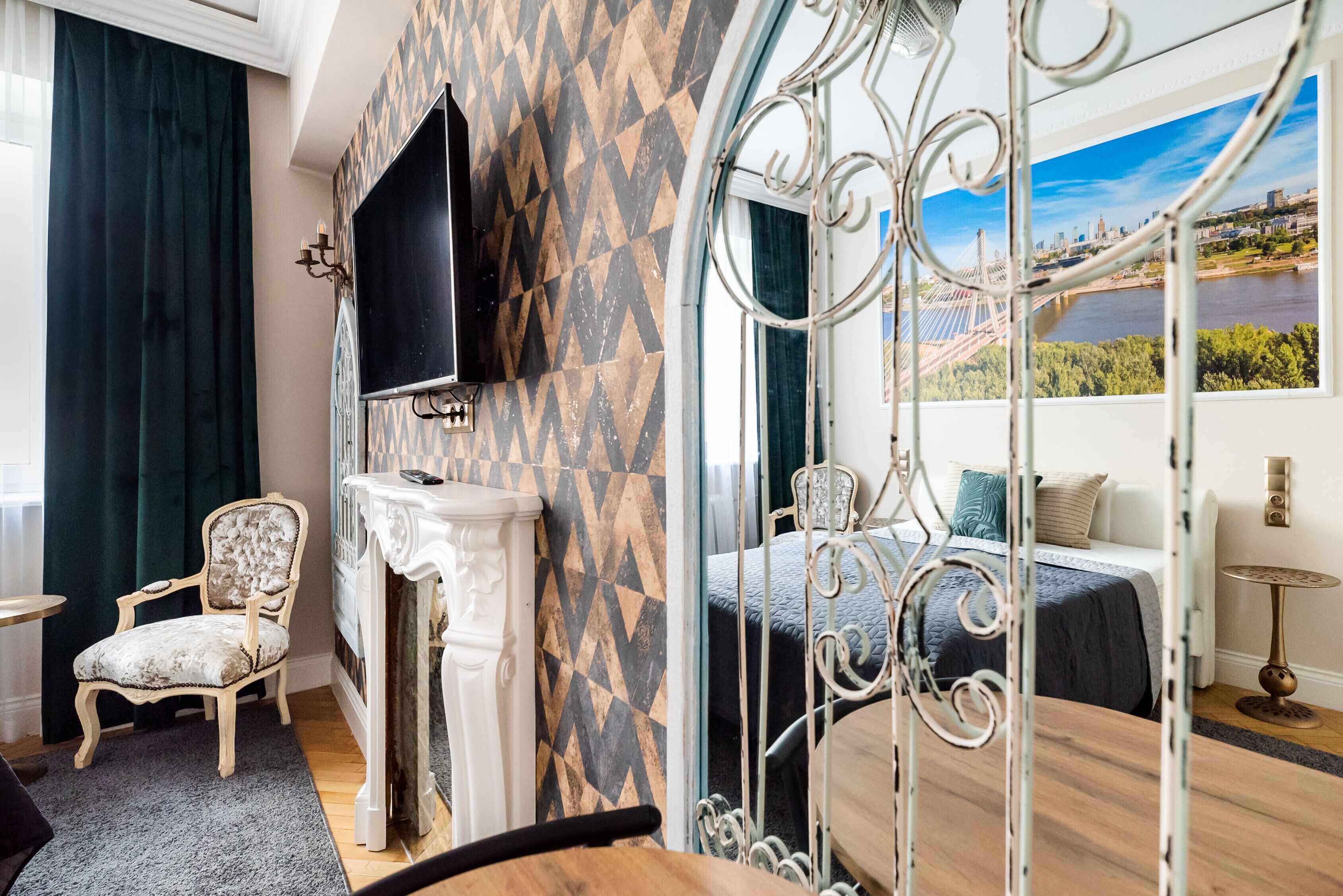Quarto com cama, televisão, poltrona e vista para a paisagem urbana pela janela.